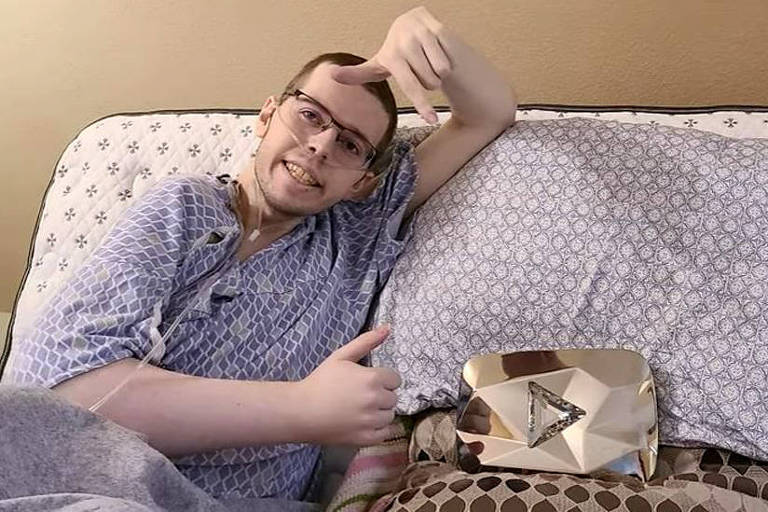 Homem branco usando óculos e tubo de respiração deitado em cama de hospital