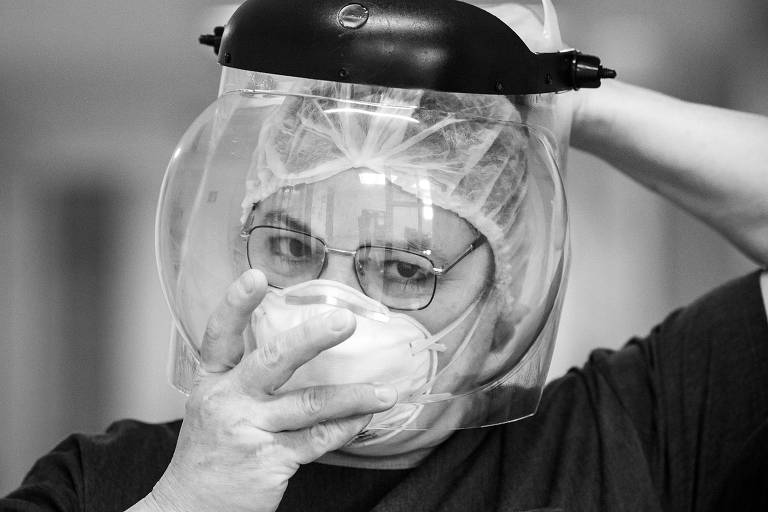 Retrato de Sandra Fernandes Barbosa, enfermeira líder da UTI adulto do Hospital Sírio-Libanês no combate à Covid. Na imagem, ela usa máscara e está colocando um face shield.