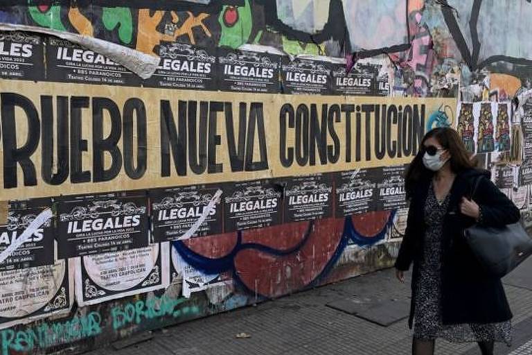 Mulher caminha em frente a cartazes políticos
