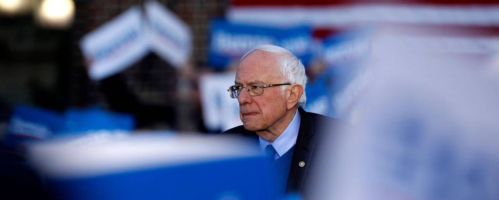 Bernie Sanders com placas de campanha no primeiro plano