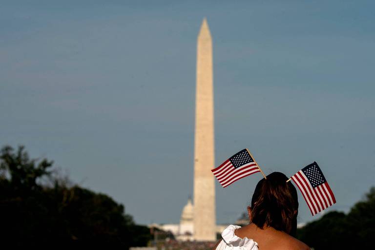 Mulher com bandeiras dos Estados Unidos durante o feriado da Independência na capital do país, Washington