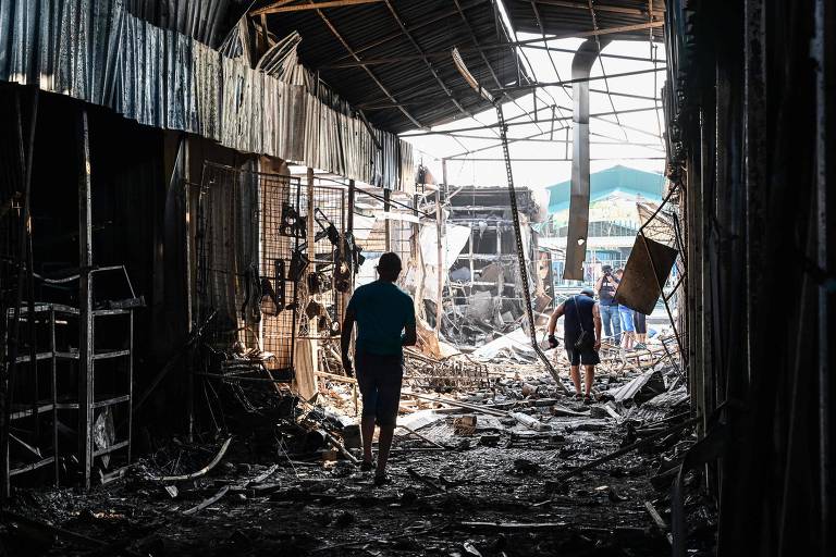 Pessoas andam em meio a destroços de mercado destruído durante bombardeio em Sloviansk, na Ucrânia