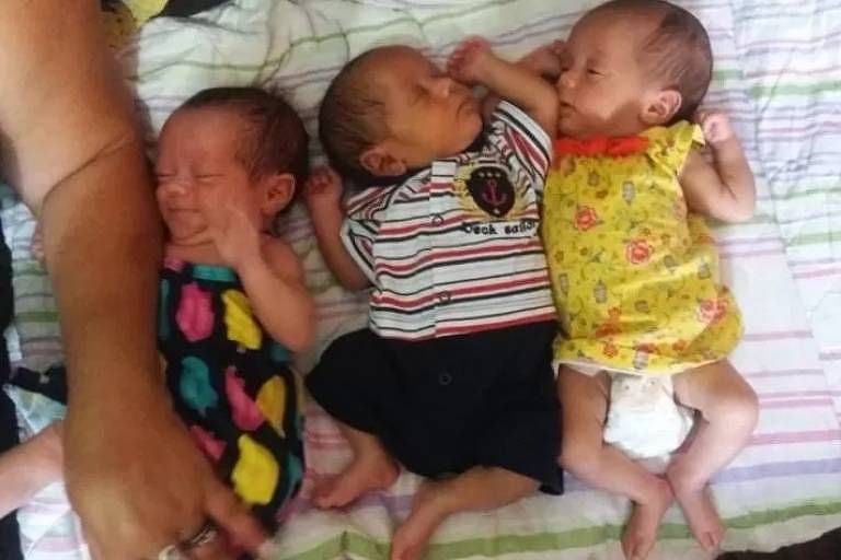 Bebês trigêmeos deitados um ao lado do outro