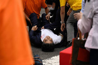 Former Japanese Prime Minister Shinzo Abe lies on the ground after he was shot during an election campaign in Nara