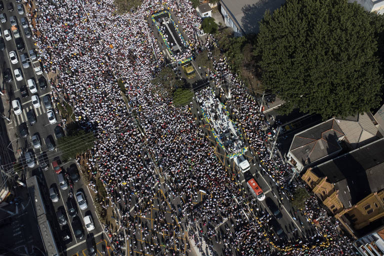 Vista aérea de rua repleta de pessoas, que cercam trios da Marcha para Jesus em São Paulo