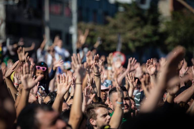 Aglomeração de pessoas com as mãos para o alto em dia de sol