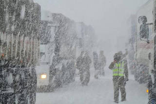 A member of the police works near vehicles on a road during a snowstorm in Los Andes, Valparaiso