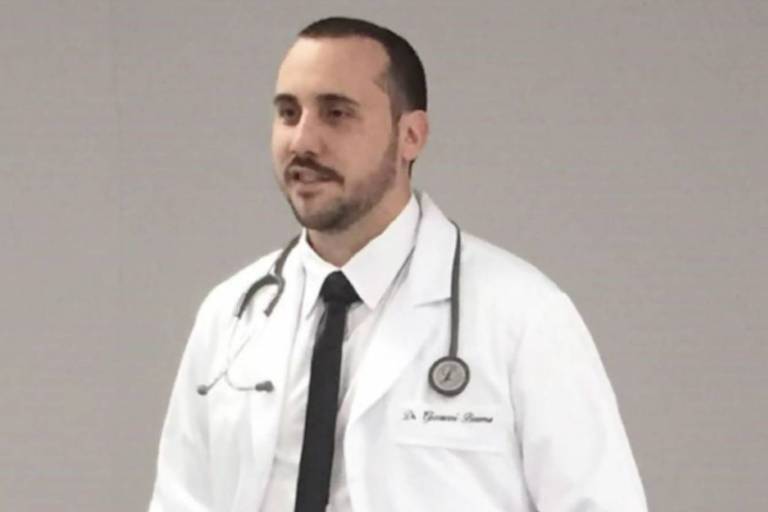 O anestesista Giovanni Quintella Bezerra veste jaleco branco, usa gravata, e um estetoscópio envolto ao pescoço