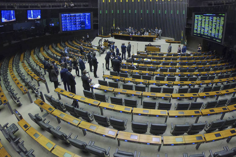 plenário em foto aberta, com poucos parlamentares presentes e muitas cadeiras vazias. Nas laterais, placares de votação