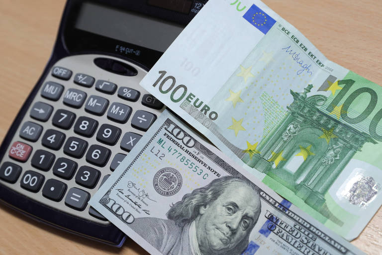 Notas de euro e dólar sobre calculadora. Moeda comum europeia atinge menor cotação em 20 anos à sombra da recessão global