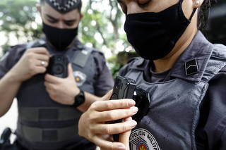 Policiais militares mostram câmeras instaladas nos uniformes, em São Paulo (SP)