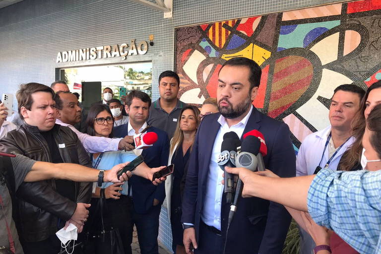 Cláudio Castro concede entrevista cercado de jornalistas com microfones de TV, câmeras e celulares