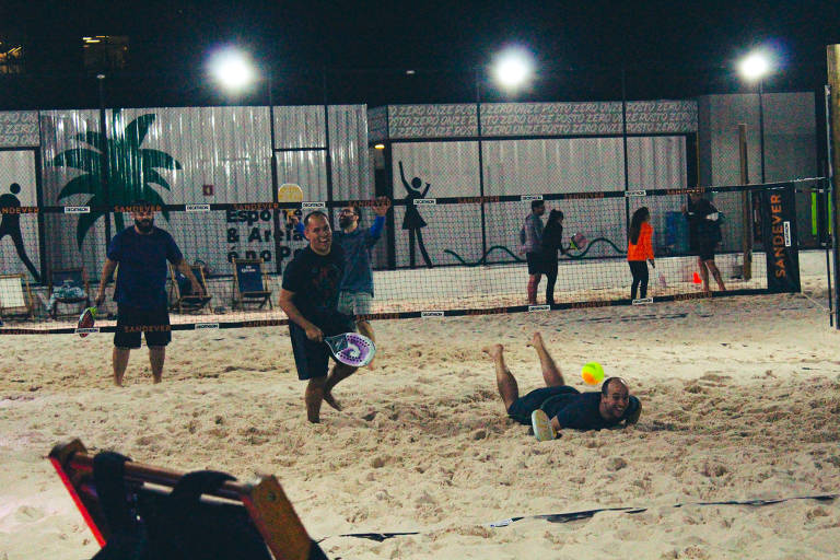 pessoas jogando tênis na areia 