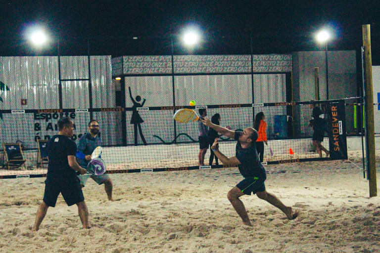 pessoas jogando tênis na areia 