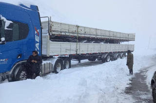 A truck driver is evacuated by from his vehicles on a road during a snowstorm in Los Andes, Valparaiso