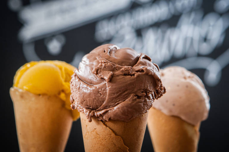 Imagem mostra três sorvetes de casquinha com o sabor de chocolate na frente