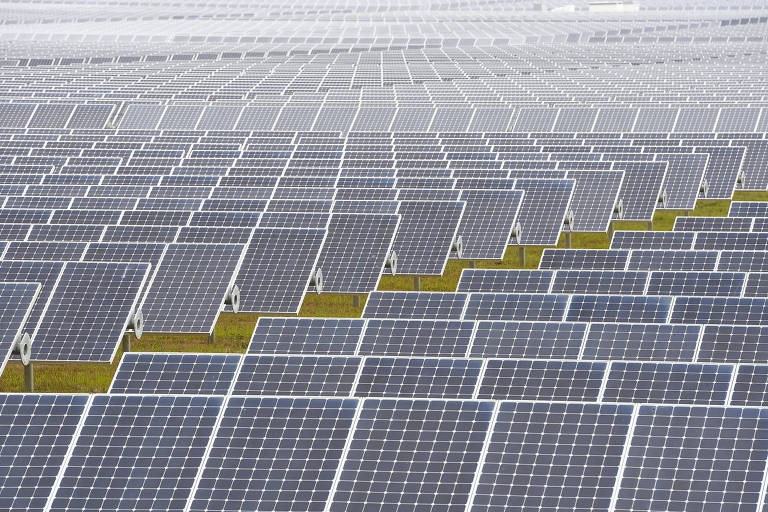 Imagem mostra vários painéis solares em um campo