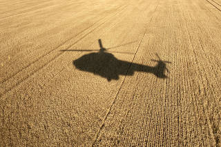 The shadow of a helicopter belonging to the Ukrainian State Emergency Service is projected on a field of wheat