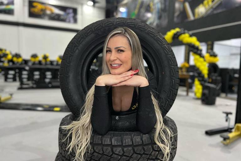 Em foto colorida, mulher entra em um pneu para fazer uma foto