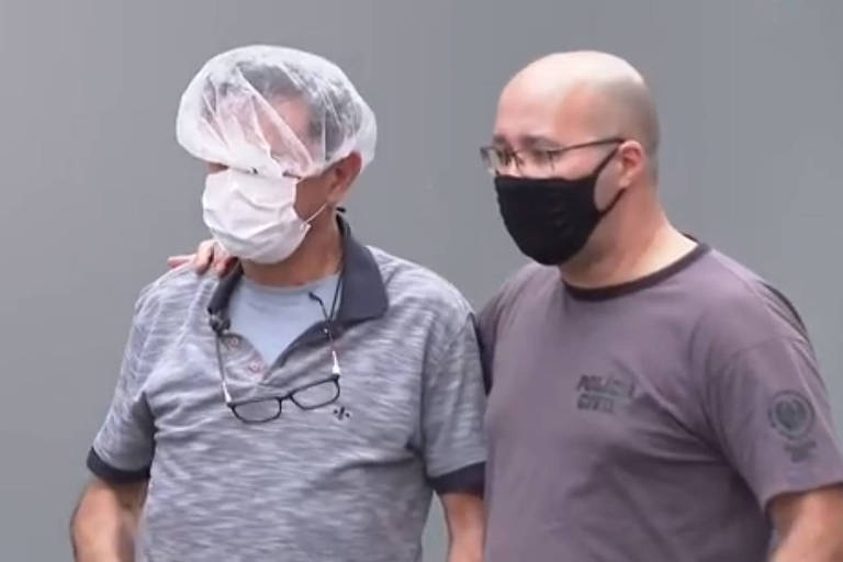 homem de touca e máscara é conduzido por policial de máscara preta