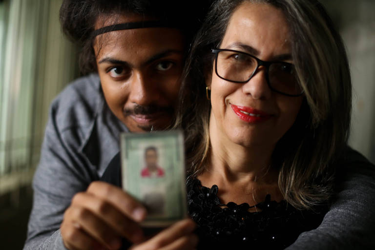 Jovem mostra a carteira de identidade ao lado da mãe