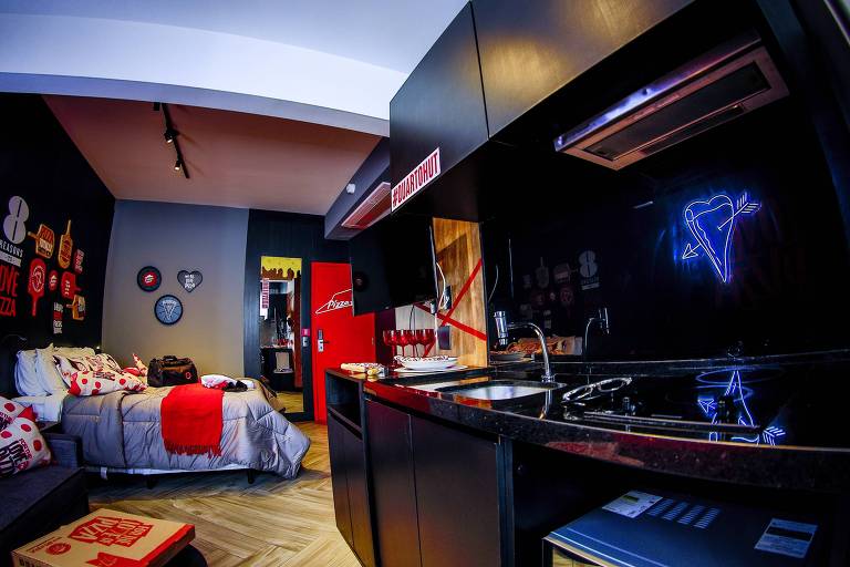 Imagem motra quarto com cama e móveis decorados pela Pizza Hut. As cores predominantes são vermelho e preto.