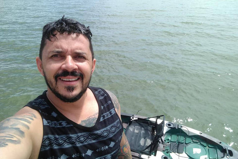 selfie de homem em rio com barco ao fundo