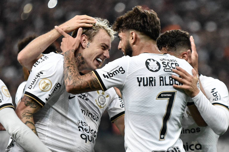 Grupo de jogadores do Corinthians, vestem camisas brancas e celebram momento do gol. Um deles colocou a bola por dentro da camiseta em referência a gravidez da esposa