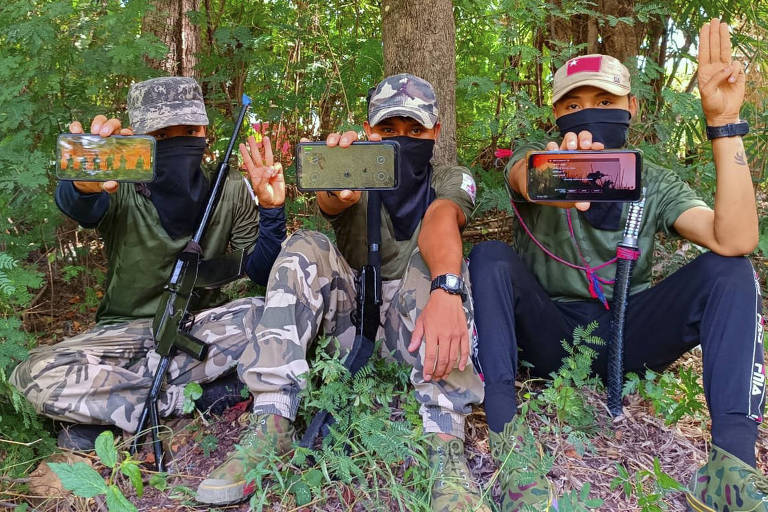 Jovens da Força de Defesa Popular exibem o jogo 'War of Heroes' em seus celulares, em Mianmar