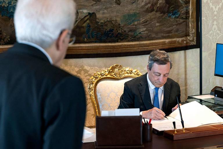 O premiê Mario Draghi, observado pelo presidente da Itália, Sergio Mattarella, assina decreto que dissolve o Parlamento após renunciar ao cargo, em Roma
