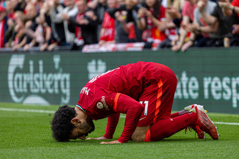 Salah se ajoelha para comemorar um gol pelo Liverpool em partida da Premier League