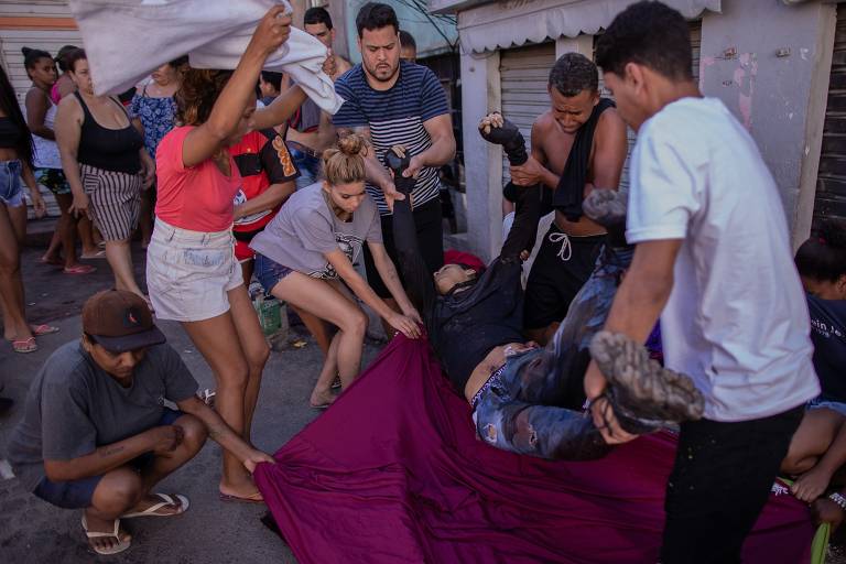 Homem baleado pela polícia é retirado por moradores; segundo a polícia, foram apreendidos uma metralhadora .50 (capaz de derrubar helicóptero), quatro fuzis e duas pistolas. Na favela da Galinha, próxima ao Alemão, quatro homens foram presos.