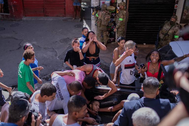 Homem baleado pela polícia é socorrido por moradores, durante operação policial no Complexo do Alemão; ouvidor da Defensoria Pública do Rio, Guilherme Pimentel afirma que recebeu relatos de muitos mortos e feridos que ainda estavam na favela à tarde e não conseguiam sair do local para serem atendidos.