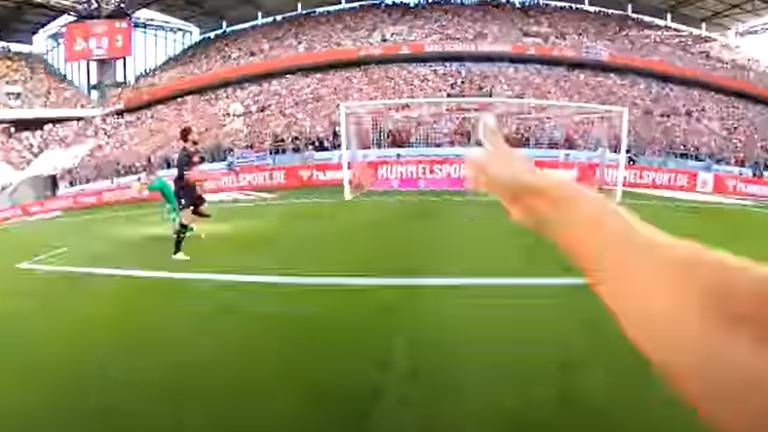 Com câmera no uniforme, Timo Hübers, do Colônia, registra, com o braço esticado, momento em que Giroud passa pelo goleiro para fazer gol do Milan