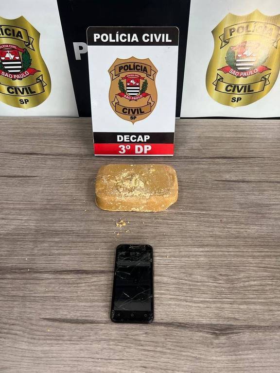 Pedra de crack e um celular fotografados em cima de uma mesa da polícia civil