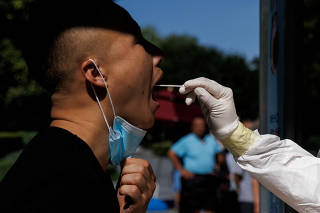 FILE PHOTO: A man gets a swab test at a nucleic acid testing station, following a coronavirus disease (COVID-19) outbreak, in Beijing
