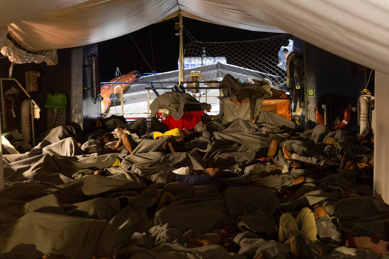 Migrantes dormem em deque de navio de resgate da ONG Sea-Watch após operação no Mar Mediterrâneo
