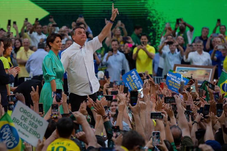 Ao lado da esposa, Michelle, Jair Bolsonaro aponta para o céu no meio de apoiadores
