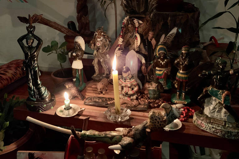 Altar com vela acesa e várias figuras religiosas 