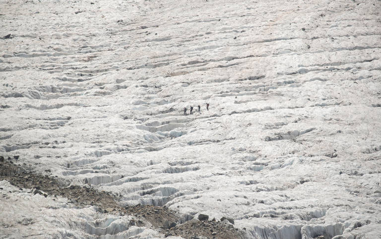 Turistas caminham pela geleira Pers; a longa língua de neve da geleira Morteratsch, que alcançava o fundo do vale, diminuiu em cerca de três quilômetros, enquanto a profundeza da neve e do bloco de gelo diminuiu em até 200 metros