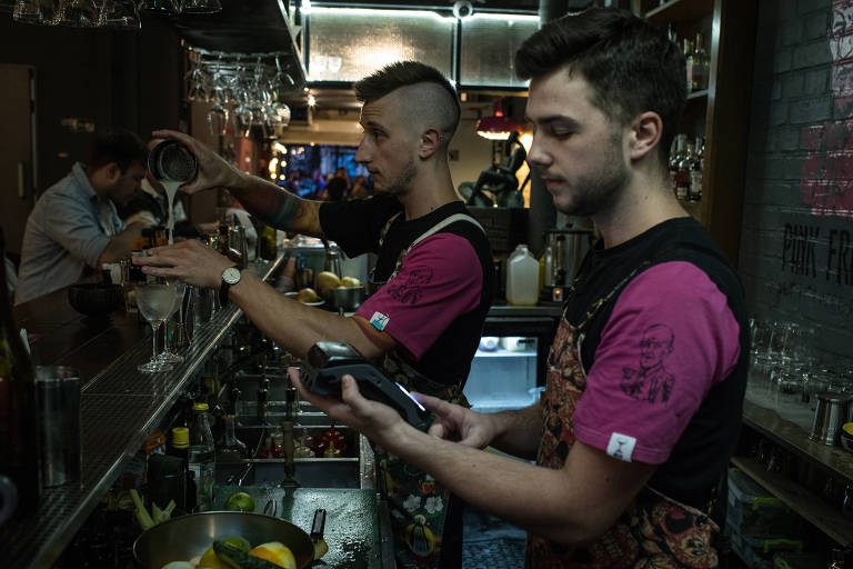 Bartenders cobram e preparam pedidos no Pink Freud, bar de Kiev, na Ucrânia