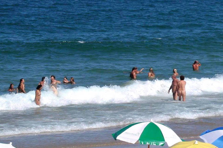pessoas nuas nadam  em uma praia