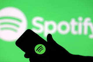 FILE PHOTO: A smartphone is seen in front of a screen projection of the Spotify logo in this picture illustration