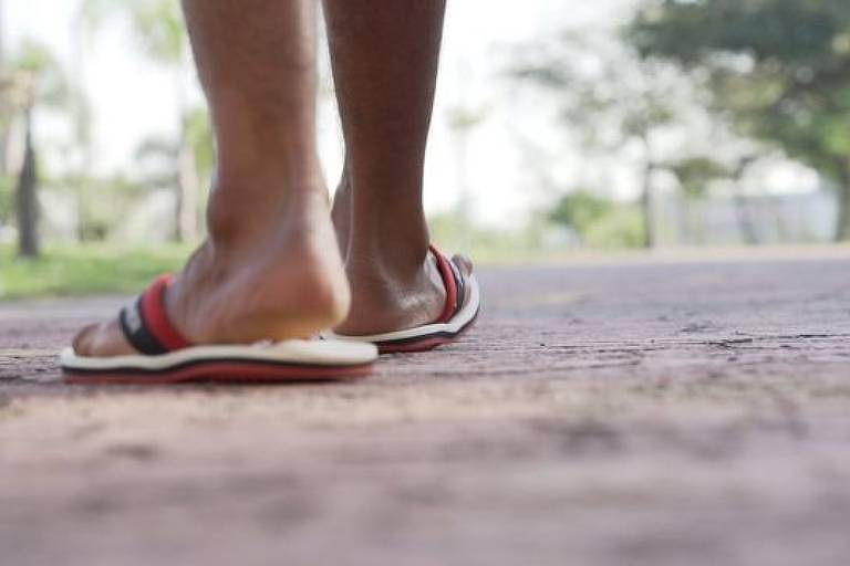 Imagem em close mostra os pés de uma pessoa de chinelo