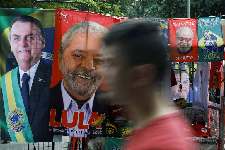 Homem passa por ambulante vendendo toalhas de Lula e Bolsonaro