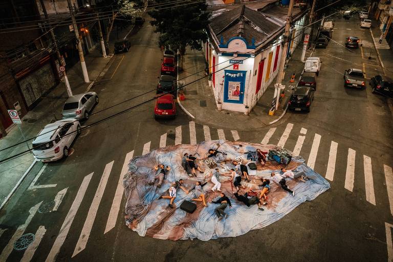 pessoas deitadas num cruzamento de avenidas em frente a um teatro