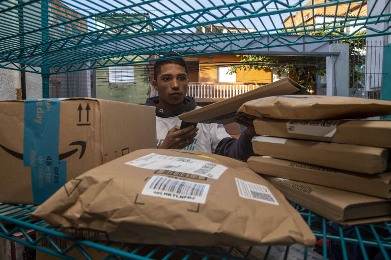 Juan Silva, 21,  prepara encomendas para distribuição da Amazon feito pela Favela Llog, em Paraisópolis, em São Paulo
