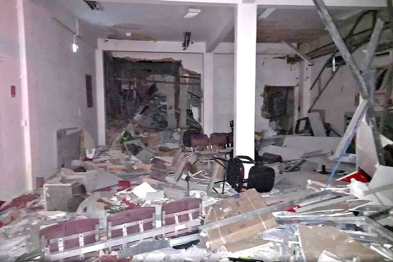 Agência revirada, com parede destruída e cadeiras espalhadas