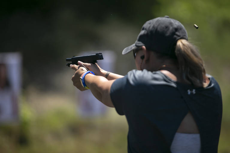 Mulher de costas atirando com uma pistola