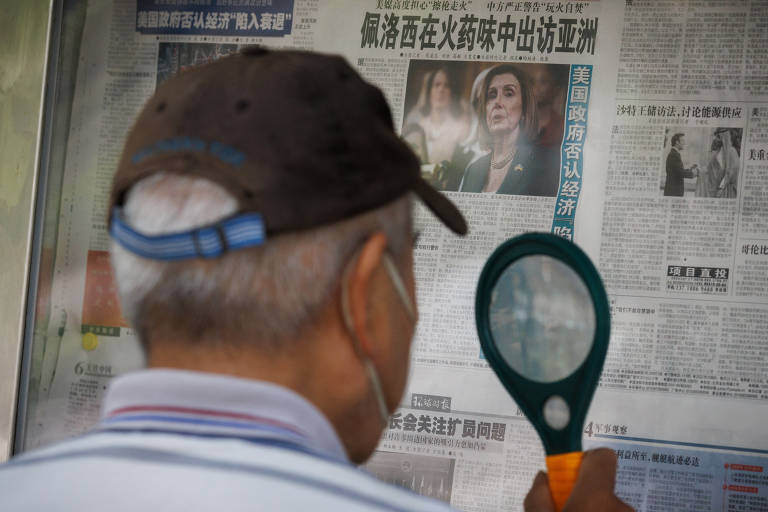 Homem com lupa lê edição do jornal Global Times, em Pequim, que mostra Nancy Pelosi, deputada americana, na capa, após anunciar viagem à Ásia